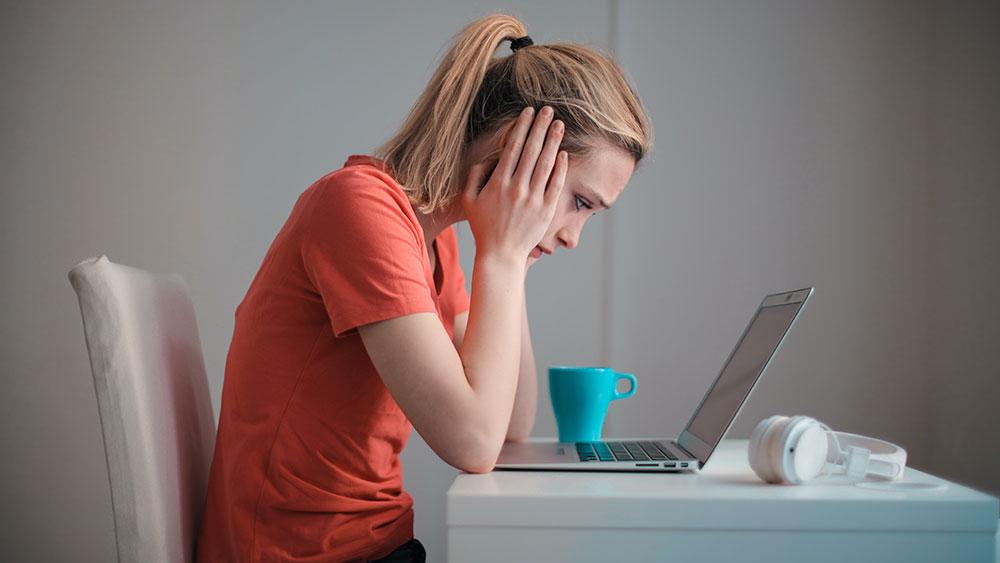 girl with hands over ears with laptop and headphones