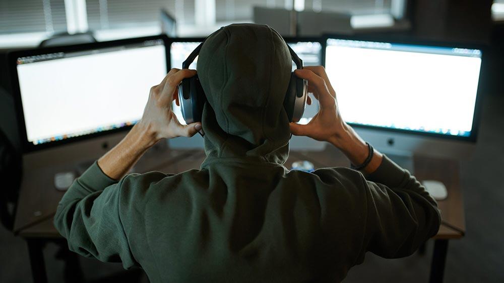 man wearing a hoodie sweatshirt with headphones on computer