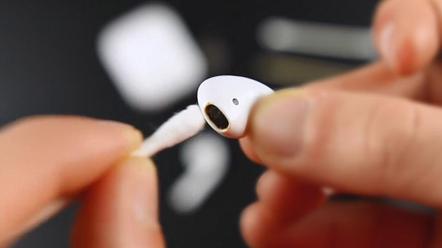 Cleaning AirPods speaker grills with a cotton swab.