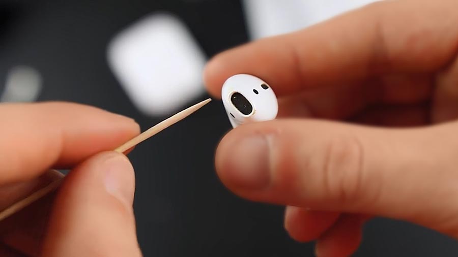 Removing debris from AirPods with a toothpick.